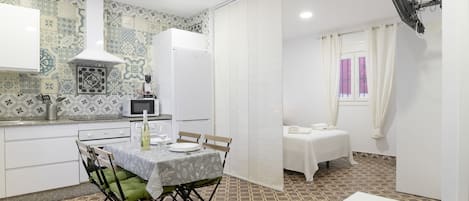 A compact kitchen with a microwave, a refrigerator, and a dining area with a table and chairs.