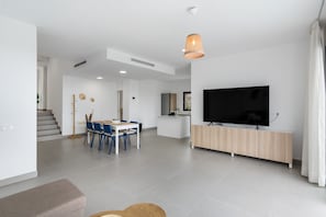Un salon moderne comprenant un coin repas, un téléviseur et un escalier menant à un autre niveau.