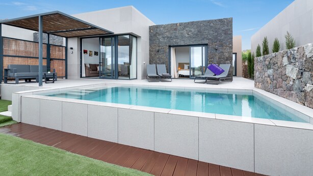 Un área moderna junto a la piscina con una pileta despejada, sillas de descanso y un espacio cubierto para sentarse.