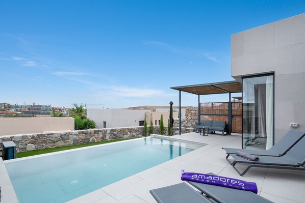 Una piscina en la azotea con sillones, una zona de estar cubierta y vistas a la ciudad.