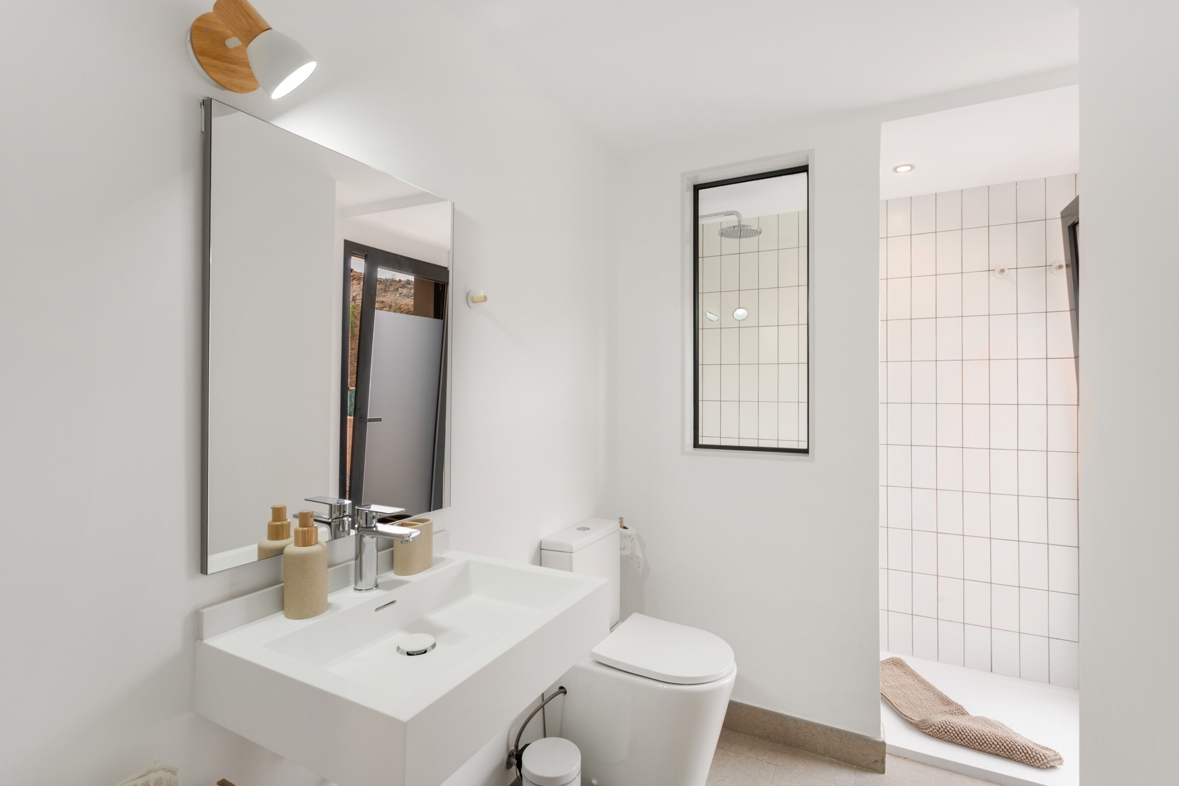 A modern bathroom with a white sink, mirror, and toilet.