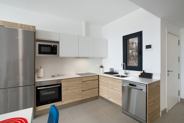Una cocina moderna con electrodomésticos de acero inoxidable, armarios de madera y una encimera blanca.