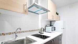 A modern kitchen with a stainless steel sink, a built-in microwave, and a kettle.