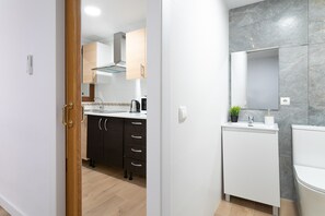 Moderni keittiö, jossa on puiset kaapit, sisäänrakennettu uuni ja kahvinkeitin.