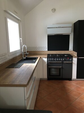 Una cocina compacta con estufa a gas, horno y un refrigerador negro.