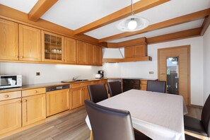 A kitchen with wooden cabinets, a microwave, a coffee maker, and a dining table with chairs.