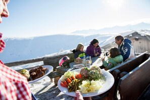 A group of people dining outdoors with a mountain view in the background.