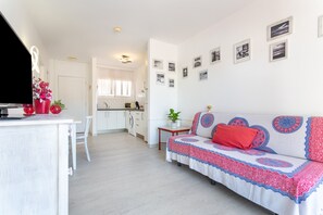 A modern living room with a sofa, a dining area, and a kitchen in the background. - Holiday Apartment 'Relax Holiday' with Shared Pool, Private Terrace and Wi-Fi (Corralejo)