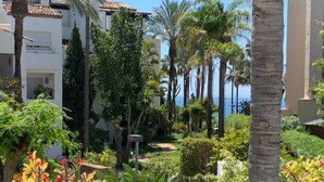A patio with a table and chairs, surrounded by palm trees and a view of the sea. - Apartment 'Apartamento De Lujo A 30m Playa' with Sea View, Wi-Fi and Air Conditioning (Estepona)
