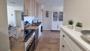 A modern kitchen with wooden cabinets, a microwave, a sink, and a countertop with potted plants. - Apartment 'New 3 Bed Family Suite In Mijas' with Wi-Fi and Air Conditioning (Las Lagunas de Mijas)