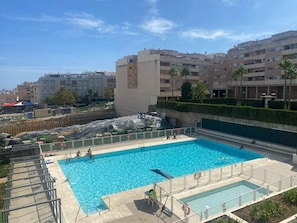 Piscina com deck cercado, rodeada por edifícios residenciais.