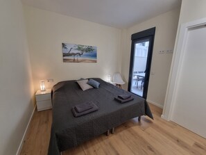 Quarto com cama, mesa de cabeceira, luminária, pintura e vista para o exterior.