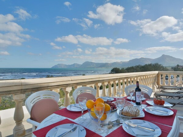 A table set for dining with a view of the sea and mountains. - Cosy Front-Line Beach Apartment in Mallorca (Son Serra de Marina)