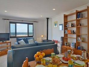 A living room with a sofa, a dining table with breakfast items, a bookshelf, and a television.
