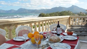 A table set for a meal with a view of the sea and mountains. - Cosy Front-Line Beach Apartment in Mallorca (Son Serra de Marina)
