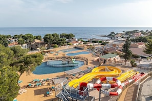 A resort with multiple swimming pools, a water slide, and a beach area.