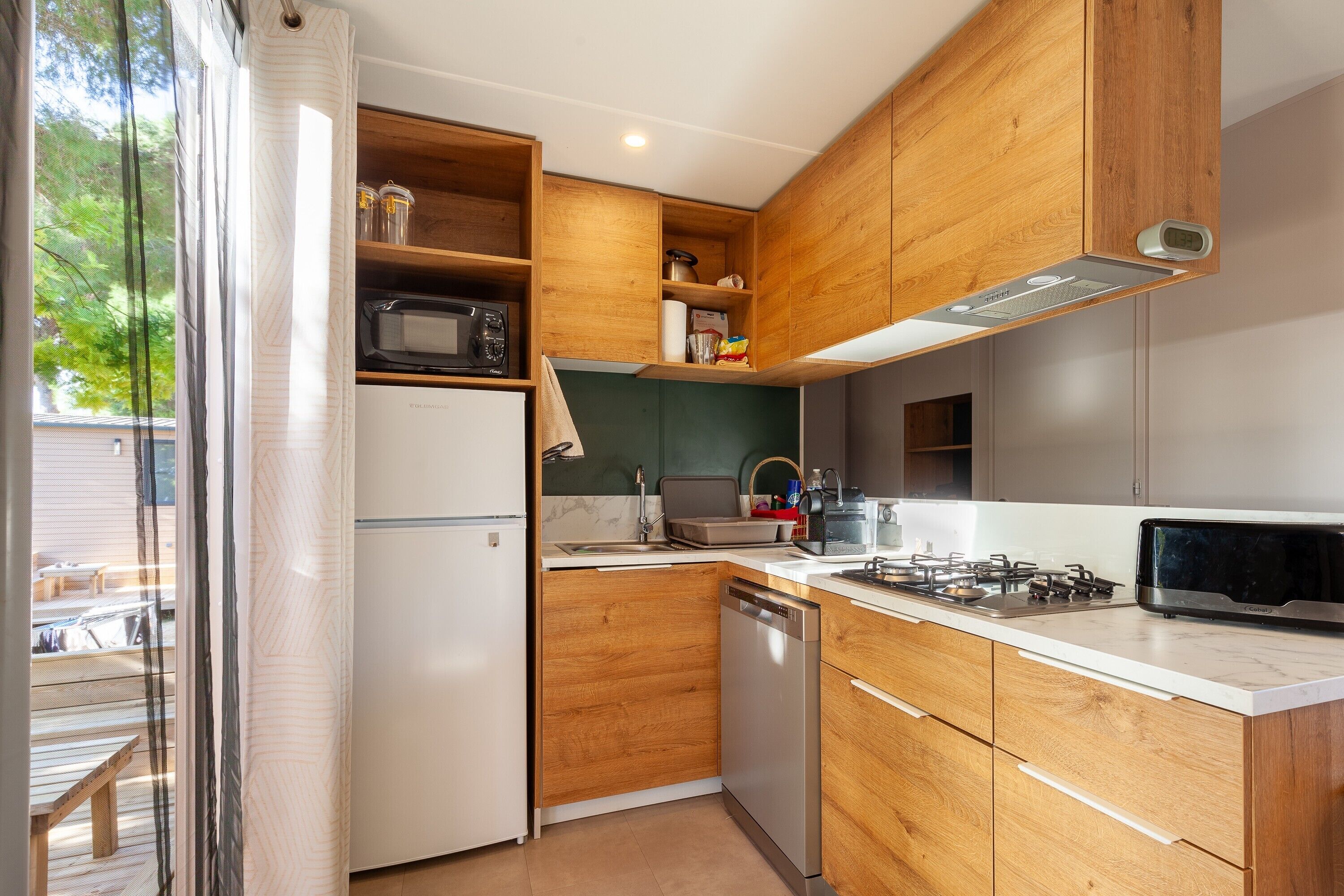 A compact kitchen with wooden cabinets, a microwave, a dishwasher, and a gas stove.