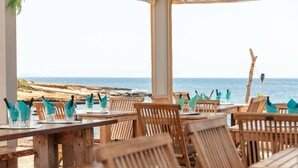 A seaside restaurant with wooden tables and chairs, arranged for dining with a view of the ocean. - Mobile Home 'Camping Lou Soulei 218' with Sea View, Shared Pool and Air Conditioning (Carry-le-Rouet)
