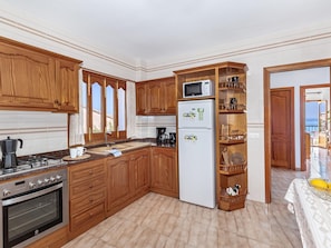 Une cuisine avec des meubles de rangement en bois, une cuisinière, un réfrigérateur et un four à micro-ondes.