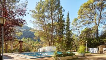 A pool area with a clear view of the surrounding trees and a mountainous backdrop.