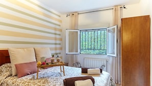 A room with a bed, a window with a view, a radiator, and a wooden door.