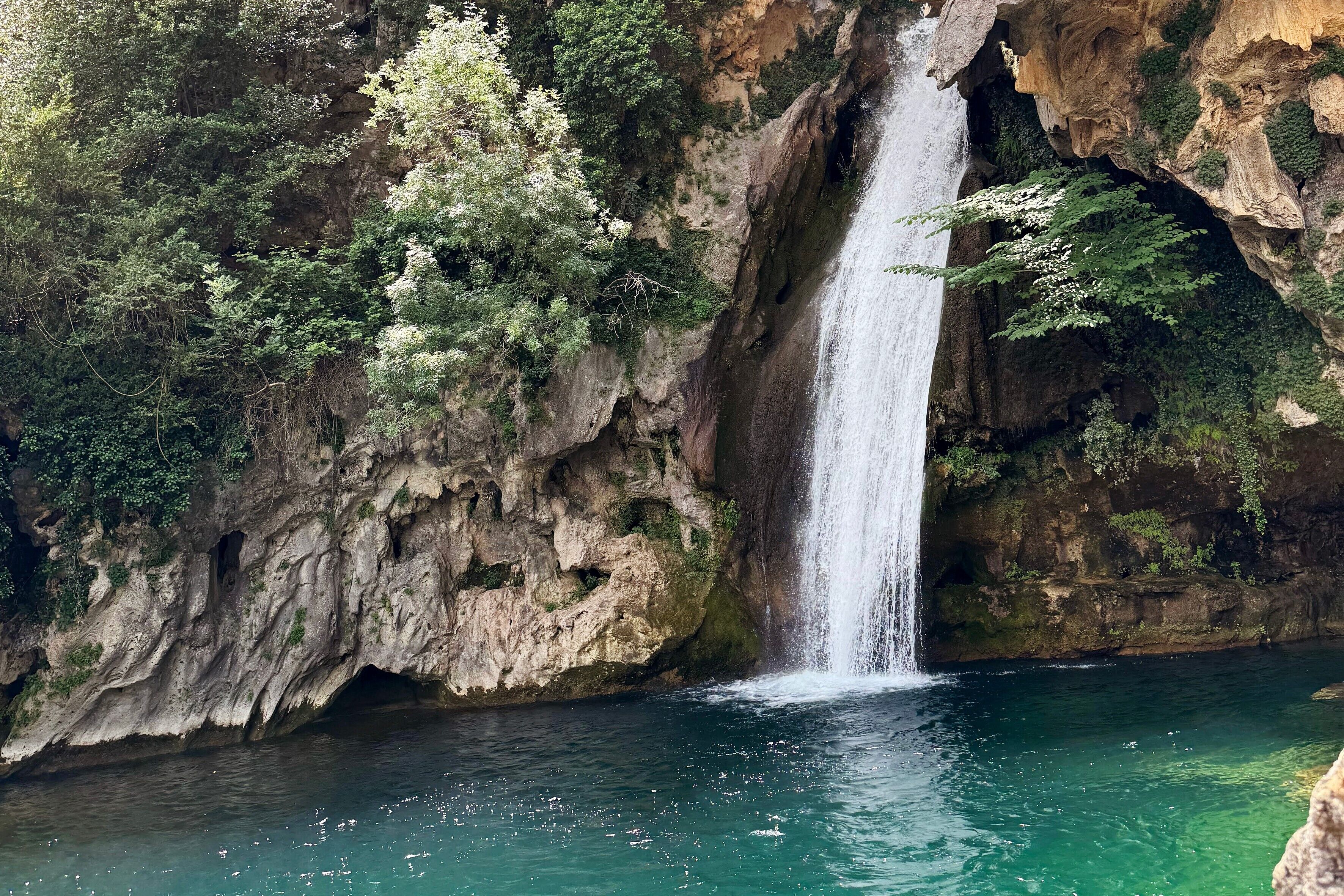 A waterfall cascading down a rocky cliff into a clear pool.