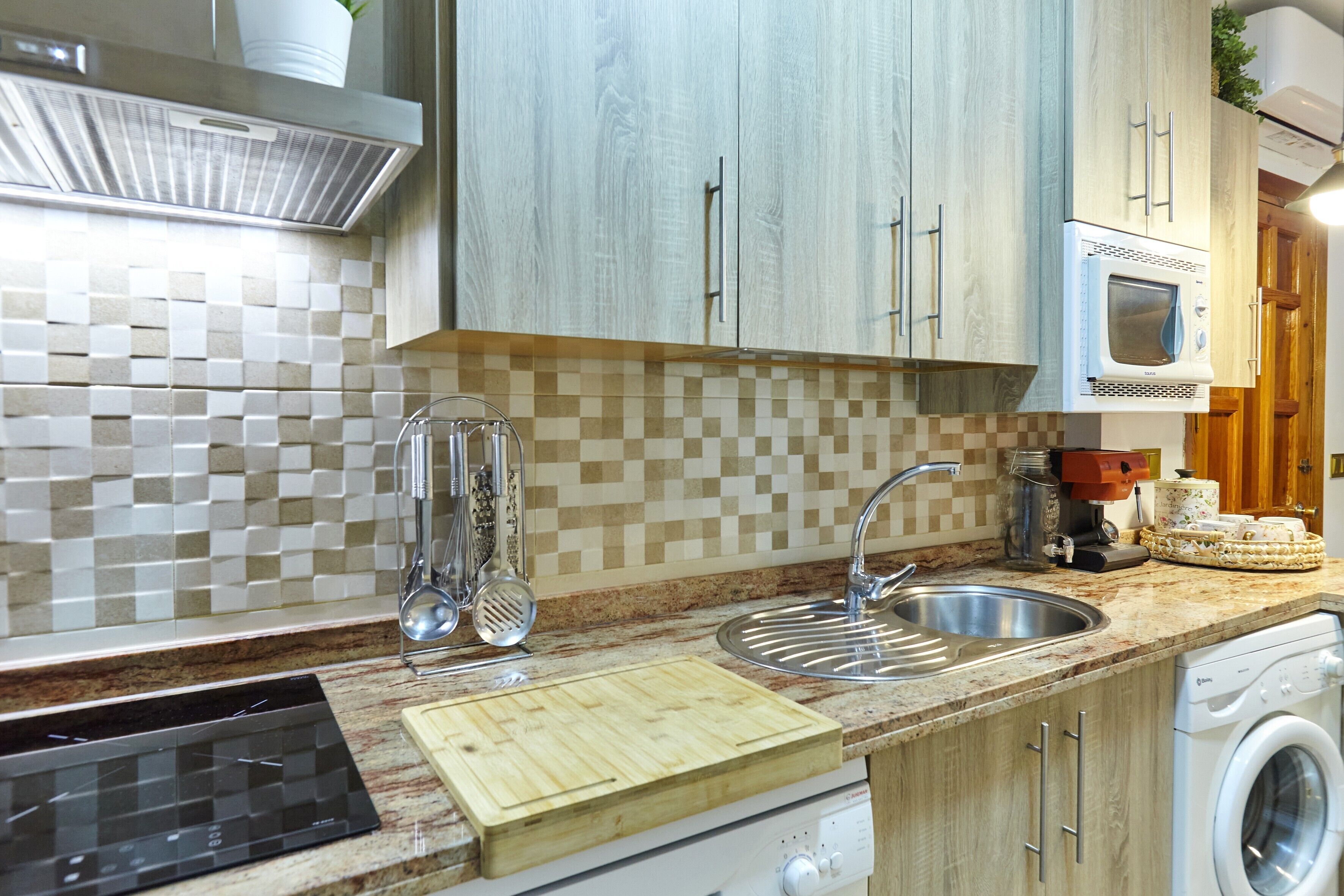A kitchen with a microwave, sink, and a wooden cutting board.