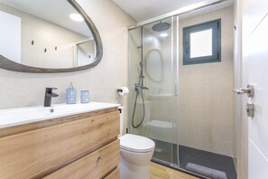 Une salle de bain avec un meuble-lavabo en bois, des toilettes, une douche en verre et un miroir.