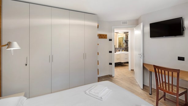 Een hotelkamer met een bed, een bureau, een televisie en een kledingkast.