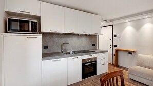 Een moderne keuken met witte kasten, een ingebouwde magnetron, een spoelbak en een oven.