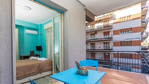 Un balcon avec un lit, une table ornée d’une sculpture et une chaise.
