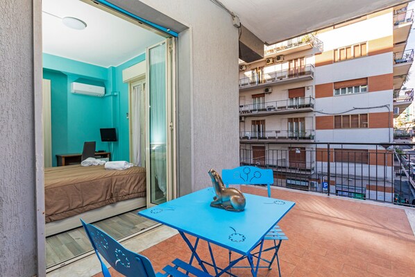 Un balcon avec un lit, une table ornée d’une sculpture et une chaise.