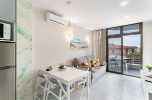 A modern living room with a dining area, a sofa, a TV, and a large window.