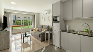 A modern kitchen with a built-in microwave, a sink, and a dining area with a sofa and a small table.