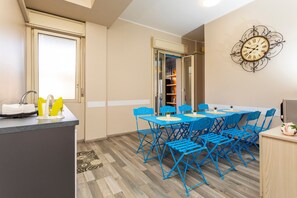 Una cocina compacta con un lavamanos, una pequeña encimera y una zona de comedor con sillas azules y una mesa.