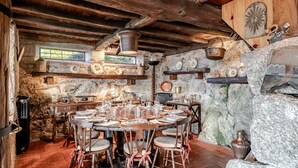 A rustic dining area with a stone wall, wooden beams, and a round table set for a meal. - Holiday Home 'Casa Do Gêres' with Lake View, Private Pool and Wi-Fi (Gêres)