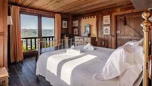 A wooden room with a bed, a desk, and a view of mountains. - Holiday Home 'Casa Do Gêres' with Lake View, Private Pool and Wi-Fi (Gêres)