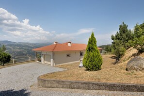 Ein Haus mit rotem Ziegeldach, einem gepflasterten Auffahrt und Blick auf die umliegende Landschaft.