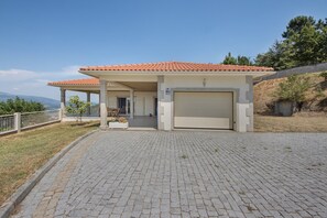 Ein Haus mit Ziegeldach, einer Garage und einem gepflasterten Einfahrtsweg.