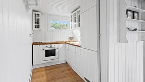 A compact kitchen with white cabinetry, a wooden countertop, and a window with a view of greenery.
