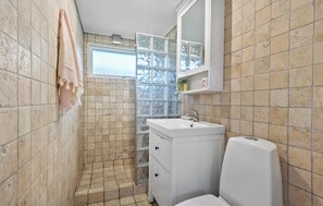 Um banheiro pequeno com janela, pia e vaso sanitário.