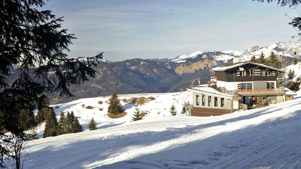 A snow-covered mountain landscape with a two-story building featuring large windows and a balcony.