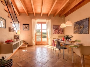Un coin repas avec une table dressée pour quatre personnes, un escalier et une vue à travers une porte vitrée.