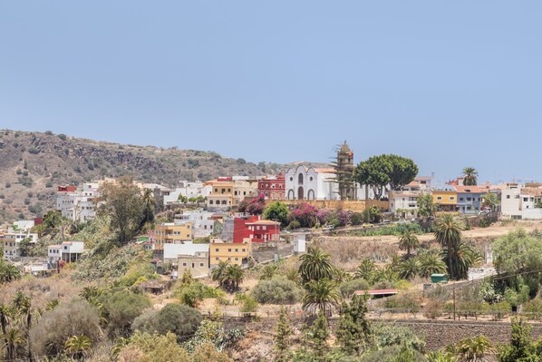 Un pueblo en una ladera con edificios coloridos, una iglesia destacada y una vía de tren.