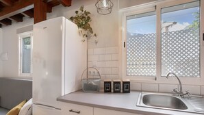 Una cocina con un refrigerador blanco, un lavamanos y una ventana que da a una cerca.