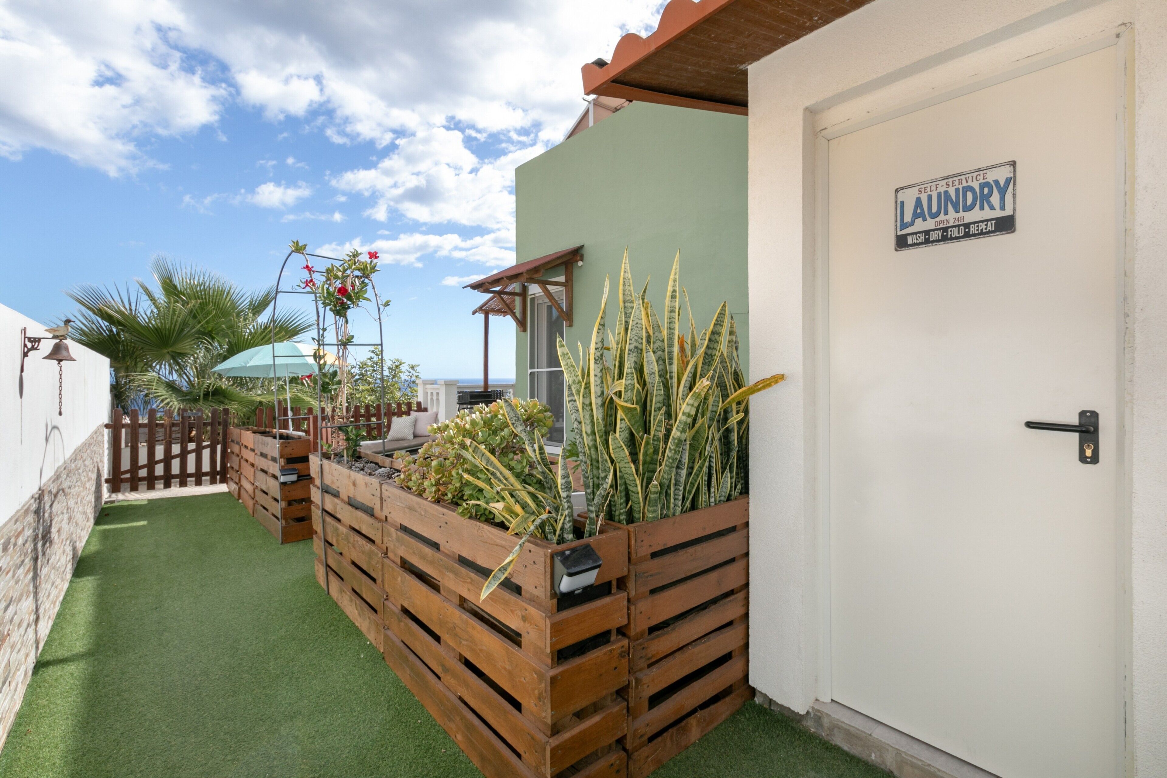 A laundry room with a sign, wooden planters with plants, and a door.