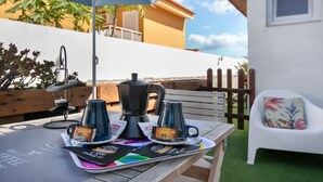 Una mesa con una cafetera, dos tazas y una bandeja con cápsulas de café.