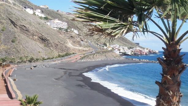 A coastal road with a beach, palm trees, and buildings in the background. - Vacation Studio 'Azahares 1 Estudio' with Sea View, Private Terrace and Wi-Fi (Candelaria)