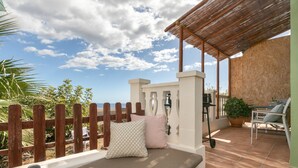 A patio with a cushioned seating area, a wooden fence, and a view of the sea. - Vacation Studio 'Azahares 1 Estudio' with Sea View, Private Terrace and Wi-Fi (Candelaria)