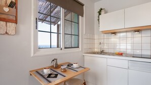 A kitchen with a window, a table with a kettle, a coffee maker, and a plant on the wall. - Vacation Studio 'Azahares 1 Estudio' with Sea View, Private Terrace and Wi-Fi (Candelaria)